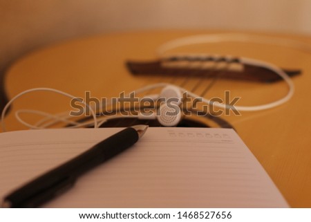 Headset notebook and pen on guitar