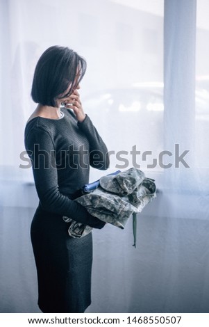 depressed woman holding military clothing at home