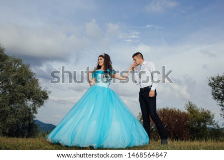 Bearded man kisses woman's hand. Guy kissing a girl's hand. A pair of lovers against the backdrop of a beautiful sky landscape
