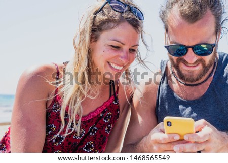 A couple in a relationship having a good time outdoors with a smartphone in summer holidays.