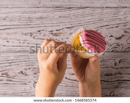 The girl takes the paper from a fresh cupcake. Freshly prepared homemade sweetness in the hands of a child.