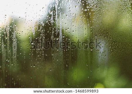 
Rain drops on glass. Green background. Wet window glass. Summer rain. Drops on the window.