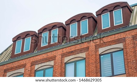 Panorama frame Close up of upper exterior of a building with red brick wall and attic windows
