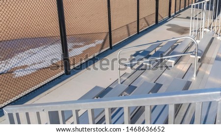 Panorama frame Bleachers behind the fence of a baseball field with melting snow on the ground