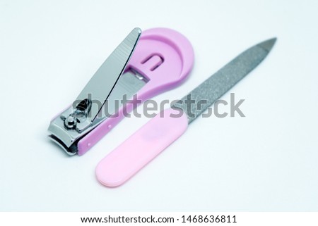 Pink nail clipper and nail file on white background.