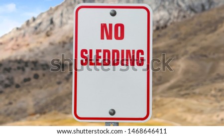 Panorama frame Close up of a No Sledding sign with a towering mountain in the background