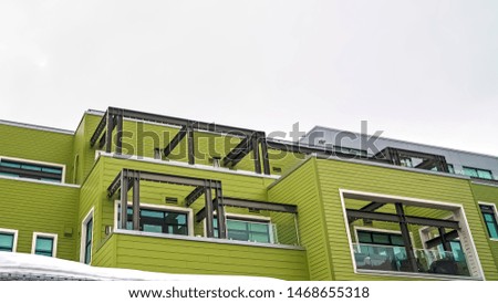 Panorama frame Building with green horizontal siding and balconies with glass railings