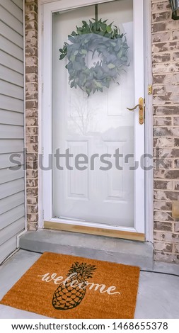 Vertical frame Facade of home with a leafy wreath hanging between the glass and wooden door