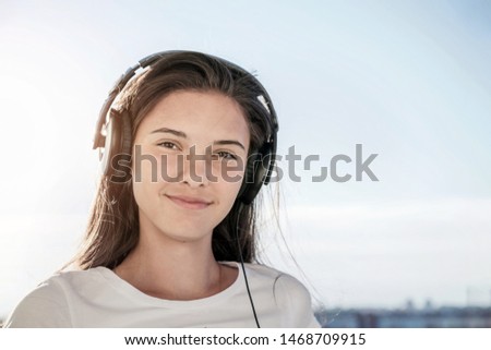 portrait of girl in headphones listening to music, blue sky background