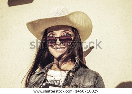 portrait of young fashion girl in hat and glasses, side view, wall background