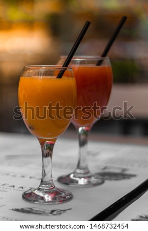 Picture of orange juice and grapefruit in glasses on table with black straws