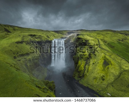 Skogafoss waterfall Iceland. Beautiful huge waterfall surrounded by green hills. Spring in Iceland.