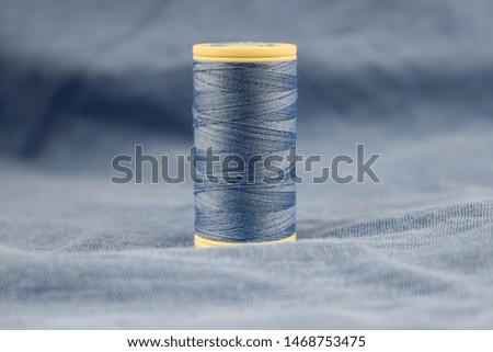blue sewing thread, blue fabric background. 
