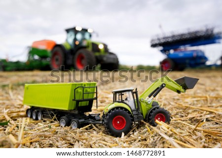 toy tractor with trailer in front of a real big tractor
