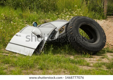 doors from the car and tires from the truck lie on the grass