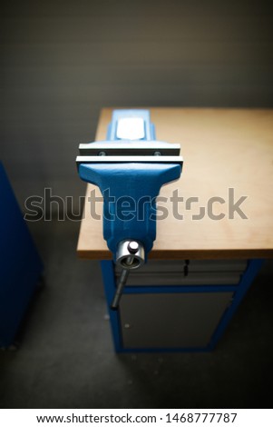Shallow depth of field image with a heavy iron vice on a workbench inside a workshop with no people around