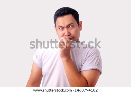 Portrait of funny young Asian man smelling his own body, bad body odor problem