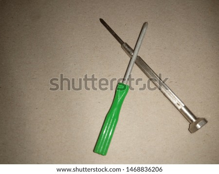 Two cross screwdrivers on the green  background.Head screwdriver with green plastic handle and Precision screwdriver ,on gray background Royalty-Free Stock Photo #1468836206