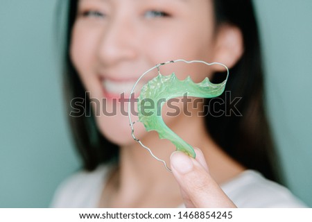 Asian woman holding orthodontic retainers.Teeth retaining tools after braces . Royalty-Free Stock Photo #1468854245