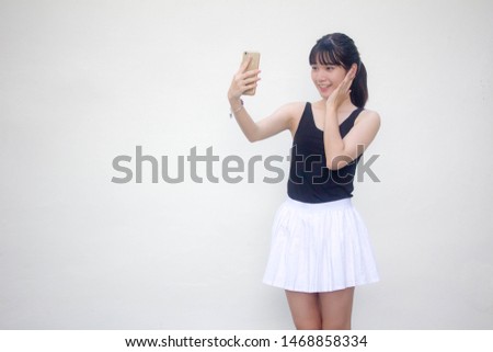 Portrait of thai adult beautiful girl black shirt white skirt using her smart phone Selfie