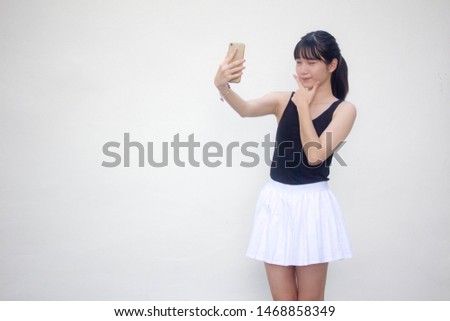 Portrait of thai adult beautiful girl black shirt white skirt using her smart phone Selfie