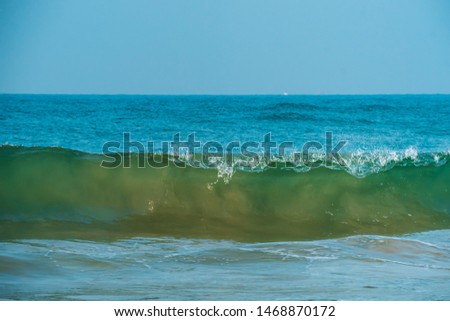 Close up of blue, green sea waves isolated in blue background. Morning with clear outdoor sky picture of shining foamy ocean high tide waters in summer, tropical beach vacation design template.