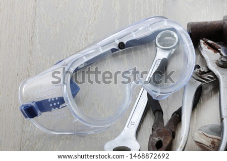 A pair of safety goggles / glasses on a bench with tools