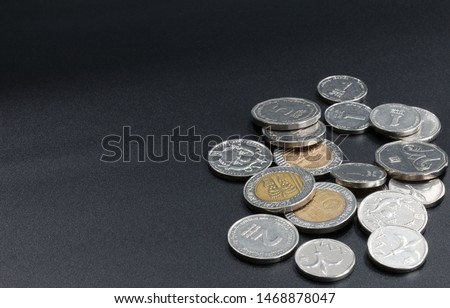 New Israeli Shekels. A scattering of coins on a black background.