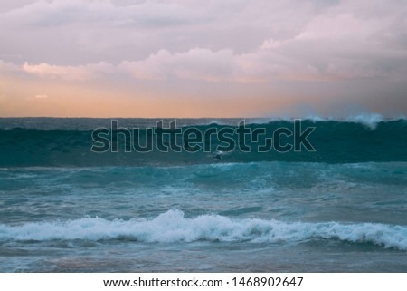 Surfer catching a wave at sunrise, Warm Sunrise colours in Background