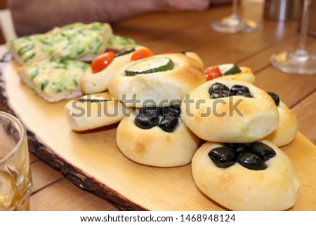 Various types of pastries and rolls with olives, zucchini and tomatoes, as well as Italian pizza. Wine and apperole served with appetizers