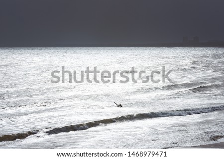 Surfer in the sea with sparkling reflection of sunlight on the sea surface