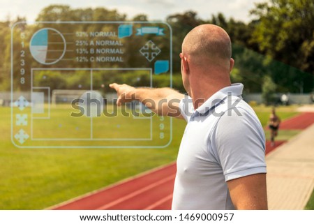 Football trainer pointing on virtual graphic icon on the football field. 