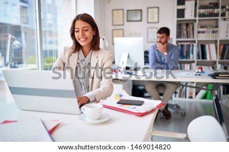 Smiling business woman at work working and looking at computer screen in the office
