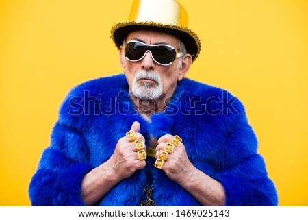 Funny and extravagant senior man posing on colored background - Youthful old man in the sixties having fun and partying Royalty-Free Stock Photo #1469025143