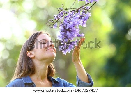 Candid woman smelling flowers standing in a park Royalty-Free Stock Photo #1469027459