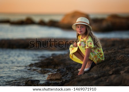 Sweet beautiful little girl of the sea at sunset. Evening walk at sunset.