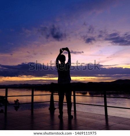 Silhouette man taking photos beautiful sunset with mobile phone