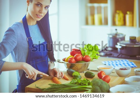Young woman cutting vegetables in kitchen at home
