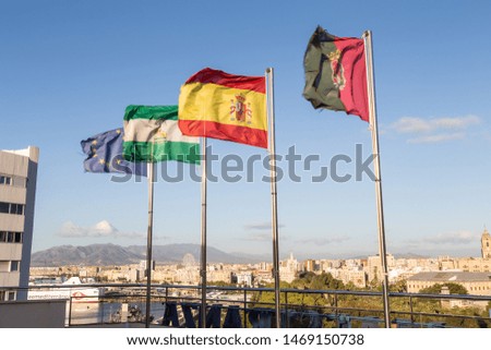European, Andalucia, Spain, and Malaga flags flying over the city scape of Malaga while traveling in Spain.