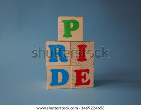 Wooden alphabet ABC toy blocks with the text: pride. Isolated kids alphabet cubes on blue background with copy space. 