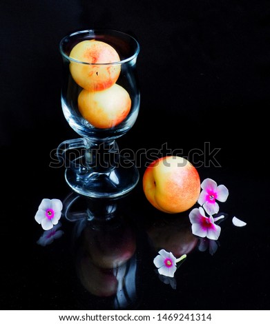  The picture shows a glass glass glass with peaches,next to pink flowers Phlox