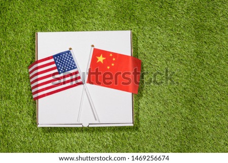 Paper box of pizza with flags of America and China on the grass. Concept of peace, partnership and friendship, . Top view