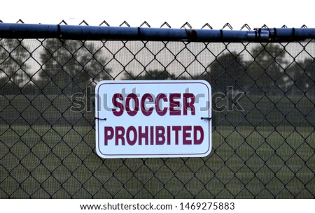 A sign that says "soccer prohibited" on a fence outside a baseball field. 