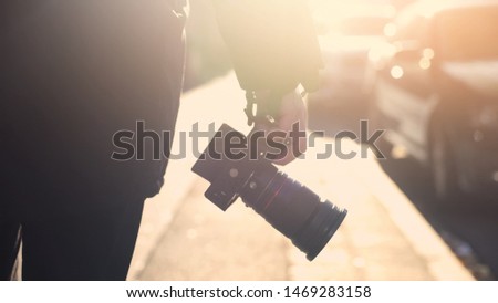 Professional photojournalist holding camera, walking on street, paparazzi spying Royalty-Free Stock Photo #1469283158