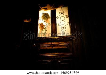 Silhouette of an unknown shadow figure on a old wooden door through a closed glass door. The silhouette of a human in front of a window at night. Scary scene halloween concept