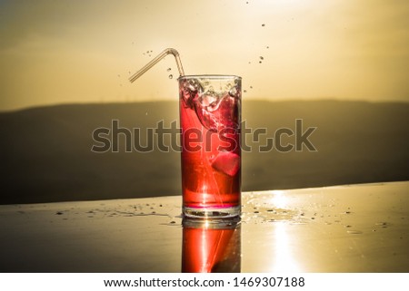 Cooling summer drink concept. Cocktail glasses splashing on sunset. Close up wet glass of cold drink on the terrace. Selective focus