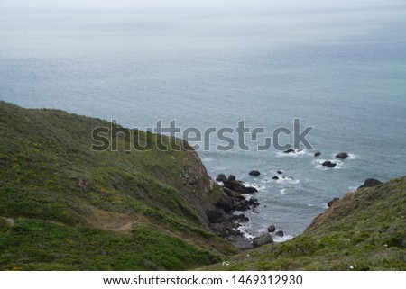 View from top of hills leading to a rocky cove in the ocean