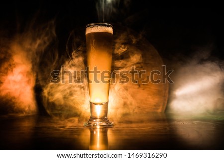 Creative concept. Single beer glass on wooden table at dark toned foggy background. Selective focus