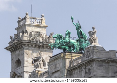 Parliament Building in Budapest. State institution in Hungary. Exterior of a historic building. Coats of arms on the wall. Statue with horses on the roof of the parliament. European architecture.