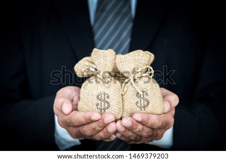 Businessman hands hold a money bags on white background give for loans to planned business investment in the future concept.